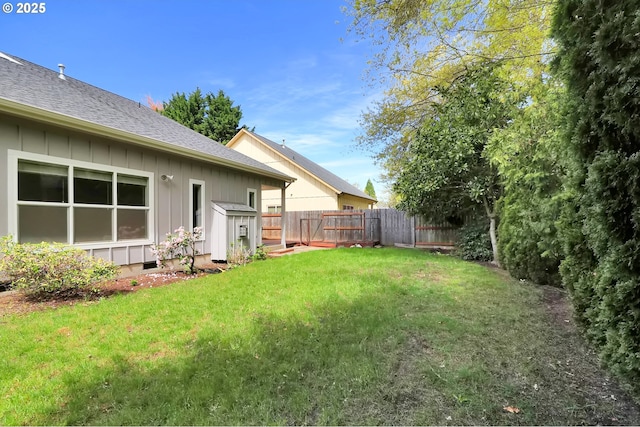 view of yard featuring fence, an outdoor structure, and a storage unit