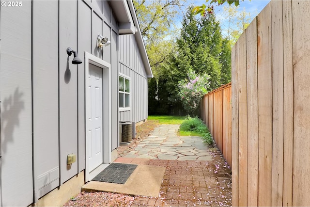 view of home's exterior with fence, board and batten siding, central AC, and a patio area