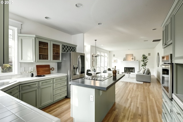 14606 NW Applegate Ln, Portland, OR 97229 - kitchen with backsplash, appliances with stainless steel finishes, a fireplace, recessed lighting, and light wood-style flooring