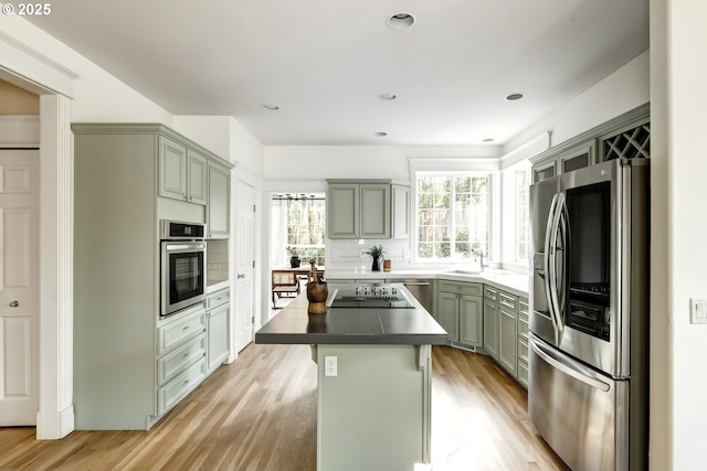 14606 NW Applegate Ln, Portland, OR 97229 - kitchen with light wood-type flooring, a sink, appliances with stainless steel finishes, and tasteful backsplash