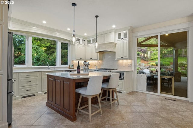 28800 SW Wildhaven Ln, Hillsboro, OR 97123 - kitchen featuring a sink, backsplash, a center island, glass insert cabinets, and a kitchen bar