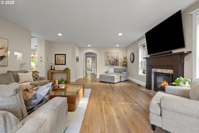 28800 SW Wildhaven Ln, Hillsboro, OR 97123 - living room featuring arched walkways, light wood-type flooring, a fireplace with flush hearth, recessed lighting, and baseboards