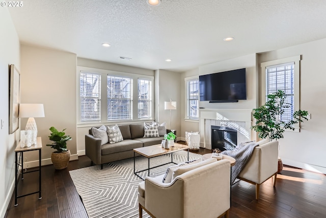 living room featuring a fireplace, a textured ceiling, and dark hardwood / wood-style flooring