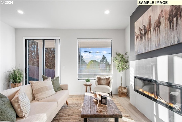 living room featuring light wood-type flooring and a tiled fireplace