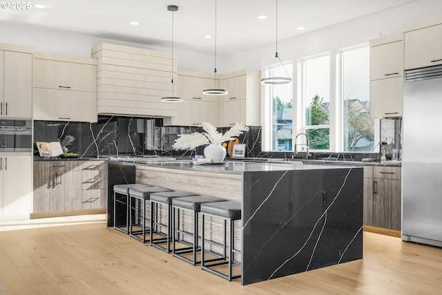 kitchen featuring cream cabinets, hanging light fixtures, and built in fridge