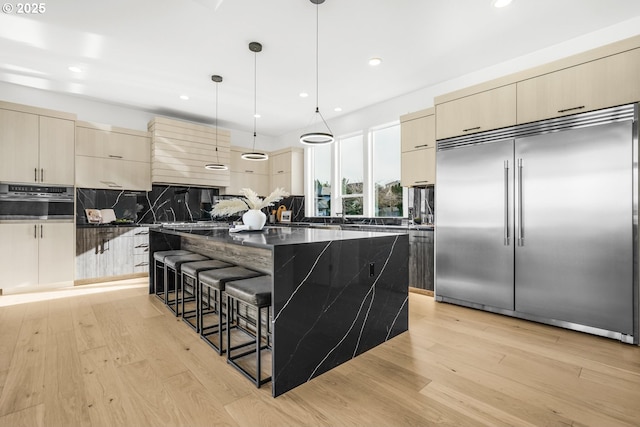 kitchen featuring a breakfast bar area, a center island, dark stone countertops, appliances with stainless steel finishes, and pendant lighting