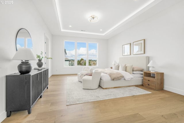 bedroom with a tray ceiling and light hardwood / wood-style floors