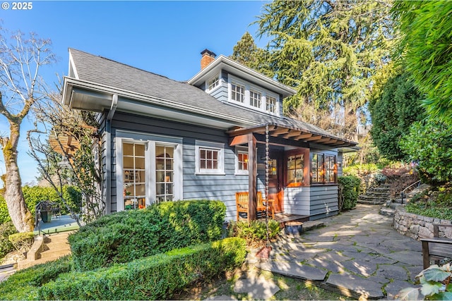 back of house featuring a chimney, a patio, and roof with shingles