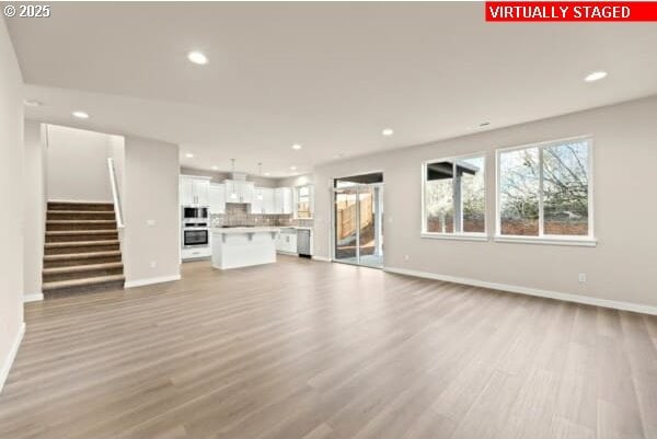 10587 SE Webelos Way, Happy Valley, OR 97086 - unfurnished living room featuring light wood-style flooring, recessed lighting, and stairway