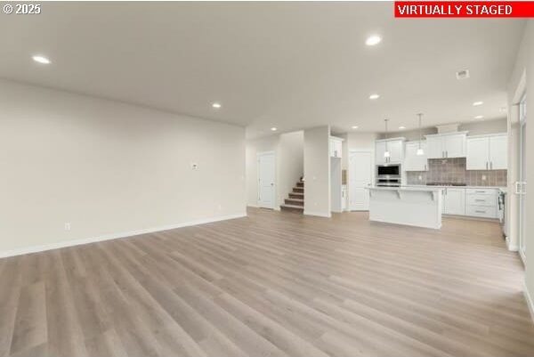 10587 SE Webelos Way, Happy Valley, OR 97086 - unfurnished living room featuring recessed lighting, light wood finished floors, and stairs