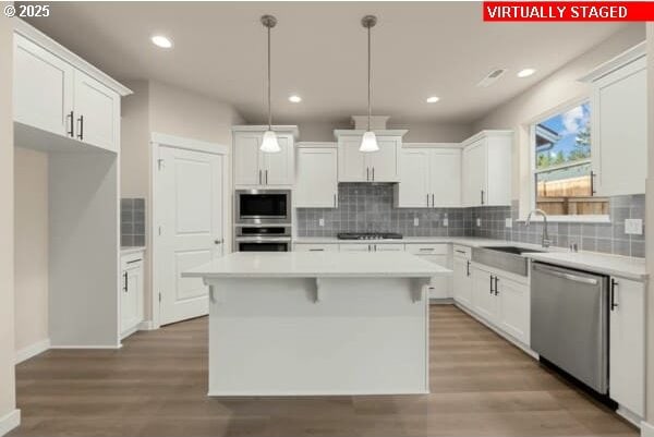 10587 SE Webelos Way, Happy Valley, OR 97086 - kitchen with stainless steel appliances, a center island, backsplash, white cabinetry, and light countertops