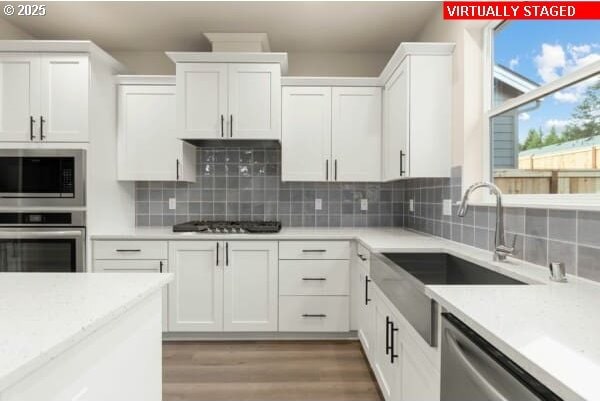 10587 SE Webelos Way, Happy Valley, OR 97086 - kitchen featuring appliances with stainless steel finishes, white cabinets, backsplash, and light wood-style flooring