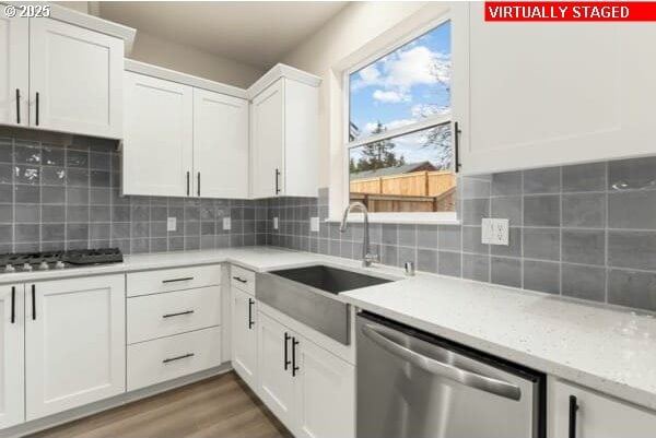10587 SE Webelos Way, Happy Valley, OR 97086 - kitchen with appliances with stainless steel finishes, white cabinets, decorative backsplash, and light wood-type flooring