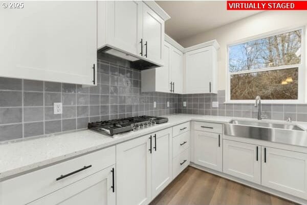 10587 SE Webelos Way, Happy Valley, OR 97086 - kitchen featuring stainless steel gas cooktop, white cabinets, dark wood finished floors, backsplash, and under cabinet range hood
