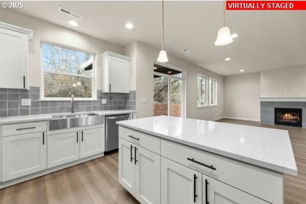10587 SE Webelos Way, Happy Valley, OR 97086 - kitchen with stainless steel dishwasher, plenty of natural light, wood finished floors, hanging light fixtures, and recessed lighting