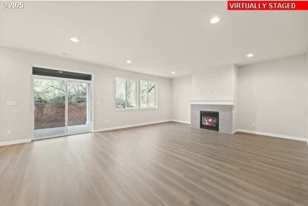 10587 SE Webelos Way, Happy Valley, OR 97086 - unfurnished living room with a glass covered fireplace, wood finished floors, and recessed lighting