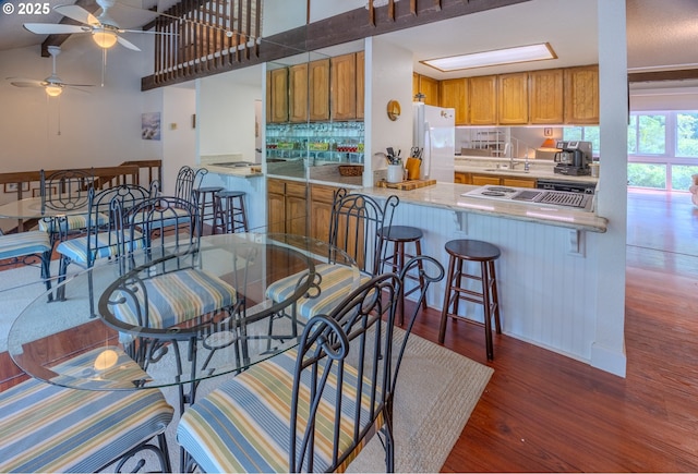 43605 State Highway 38 Unit 41, Reedsport, OR 97467 - kitchen featuring freestanding refrigerator, wood finished floors, decorative backsplash, brown cabinets, and ceiling fan