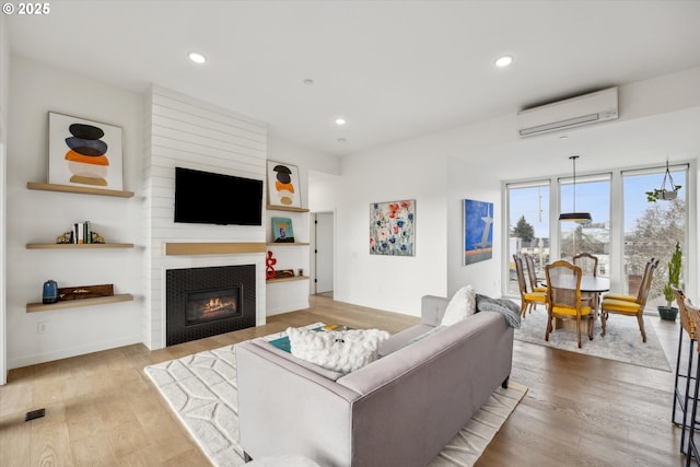 living room with hardwood / wood-style floors, a fireplace, and an AC wall unit