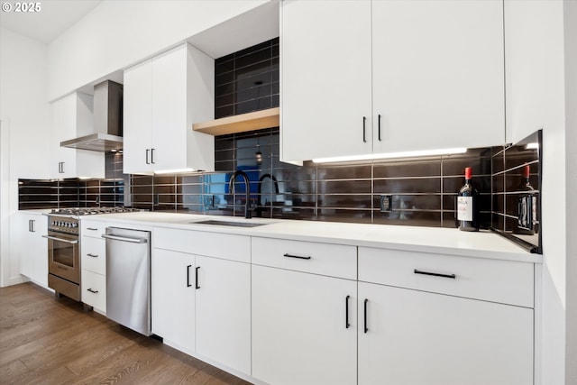 kitchen featuring sink, stainless steel appliances, white cabinets, backsplash, and wall chimney range hood