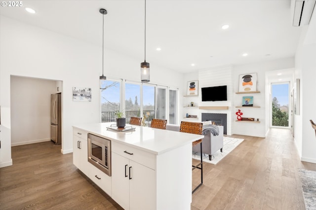 kitchen with pendant lighting, a center island, stainless steel appliances, white cabinetry, and a kitchen breakfast bar