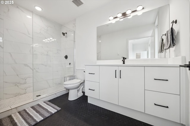 bathroom with a tile shower, vanity, and toilet