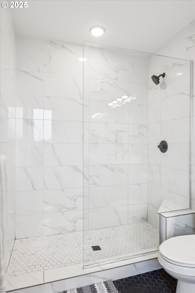 bathroom featuring toilet, tiled shower, and tile patterned floors