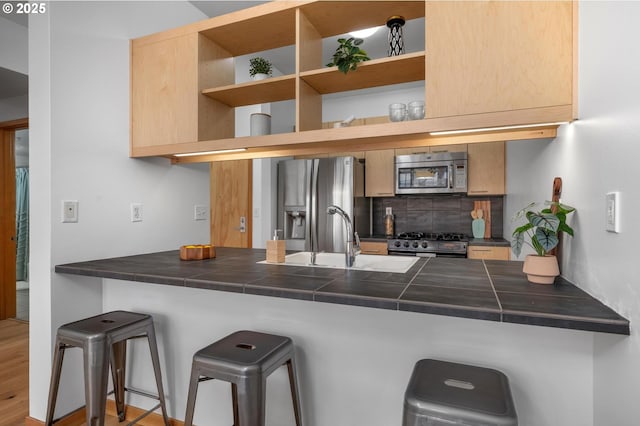 725 NW 10th Ave Unit 503, Portland, OR 97209 - kitchen featuring stainless steel appliances, a peninsula, tasteful backsplash, and a breakfast bar area