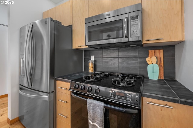 725 NW 10th Ave Unit 503, Portland, OR 97209 - kitchen featuring stainless steel appliances, backsplash, tile counters, and light brown cabinetry