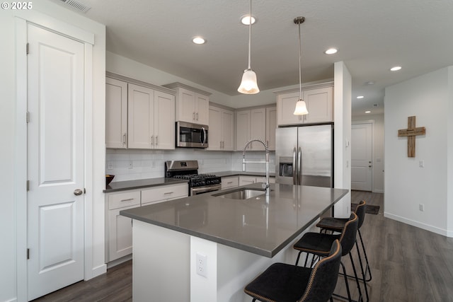 24200 SW Chestnut Ter, Sherwood, OR 97140 - kitchen with stainless steel appliances, dark countertops, tasteful backsplash, dark wood-style floors, and a breakfast bar