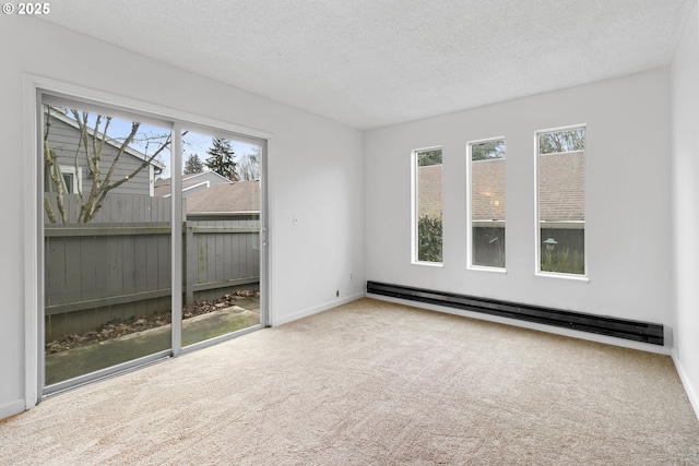 spare room with carpet floors, a baseboard heating unit, and a textured ceiling