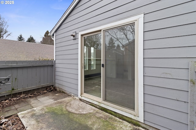 view of exterior entry featuring a patio area and fence