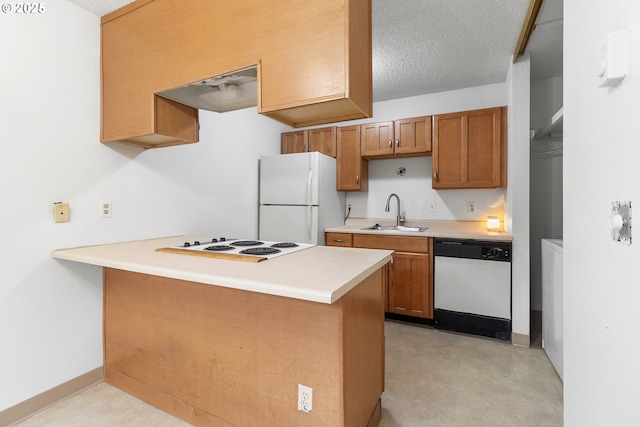 kitchen featuring white appliances, a peninsula, light countertops, a textured ceiling, and a sink