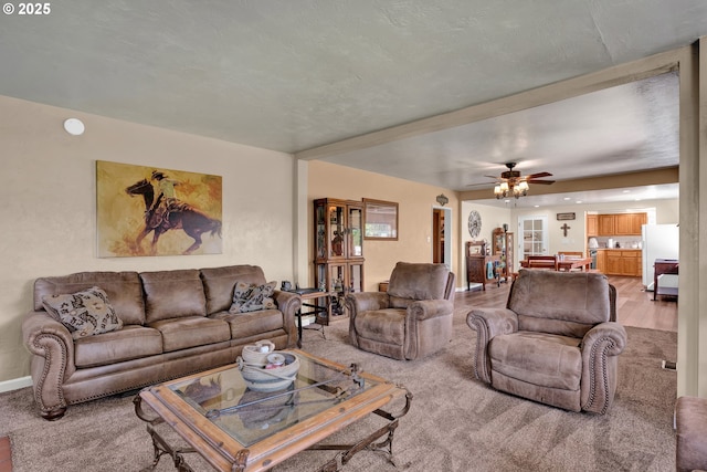 living room featuring light carpet, a ceiling fan, and baseboards