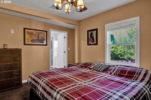 bedroom with a textured wall, a chandelier, dark carpet, and baseboards