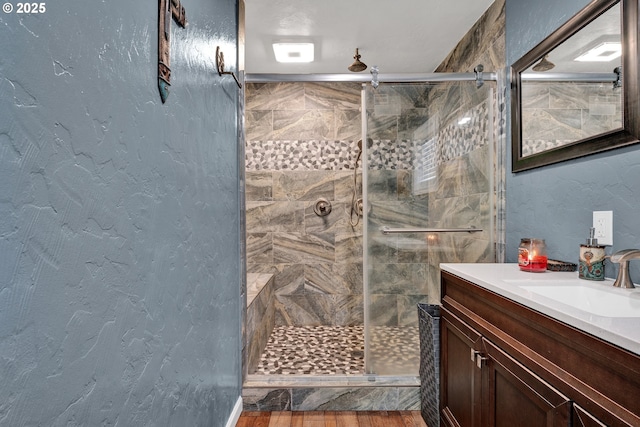 bathroom featuring a shower stall, vanity, and a textured wall