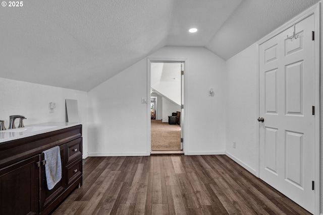 bonus room with lofted ceiling, a sink, dark wood-style floors, a textured ceiling, and baseboards