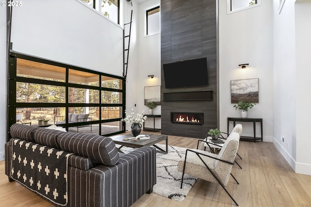 19550 Buck Canyon Rd, Bend, OR 97702 - living area featuring baseboards, a high ceiling, a fireplace, and wood finished floors