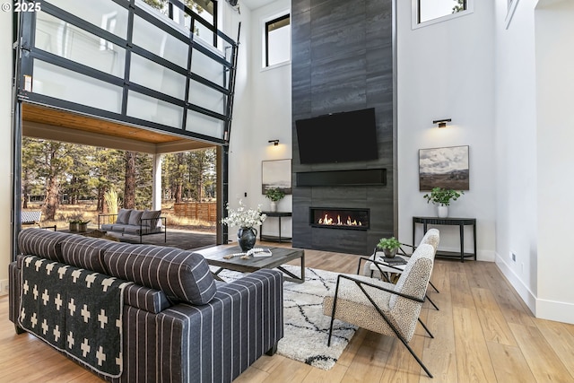 19550 Buck Canyon Rd, Bend, OR 97702 - living area featuring a high ceiling, baseboards, hardwood / wood-style flooring, and a tile fireplace