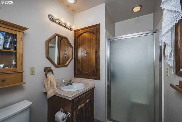 bathroom with toilet, a shower stall, and vanity