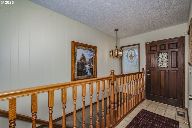 entrance foyer with a chandelier, light tile patterned floors, a textured ceiling, and visible vents