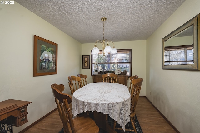 dining space featuring baseboards, dark wood-style flooring, a textured ceiling, and an inviting chandelier