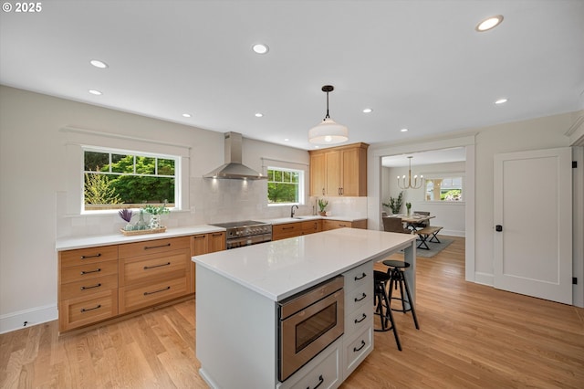 4072 NE 24th Ave, Portland, OR 97212 - kitchen featuring wall chimney range hood, stainless steel appliances, a sink, light wood-type flooring, and recessed lighting