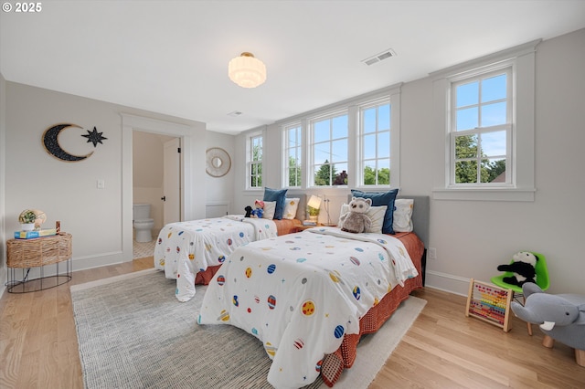 4072 NE 24th Ave, Portland, OR 97212 - bedroom with multiple windows, wood finished floors, baseboards, and ensuite bathroom