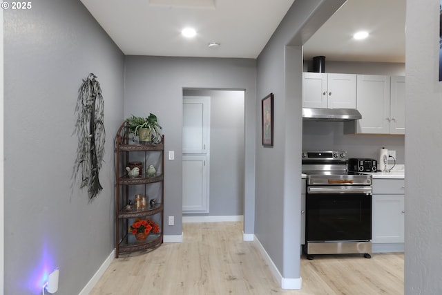 kitchen featuring electric range, light countertops, baseboards, under cabinet range hood, and light wood-style flooring