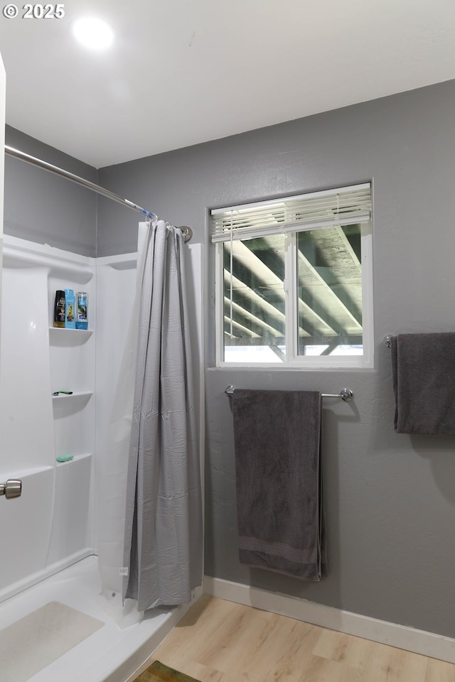 bathroom with baseboards, wood finished floors, and a shower with curtain