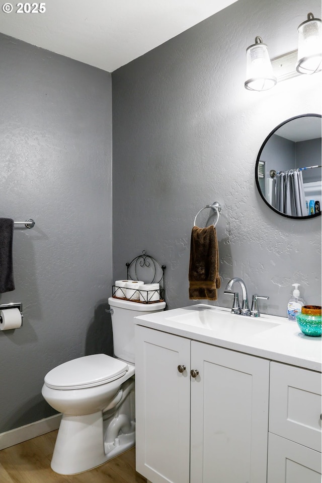 full bath with toilet, wood finished floors, and vanity
