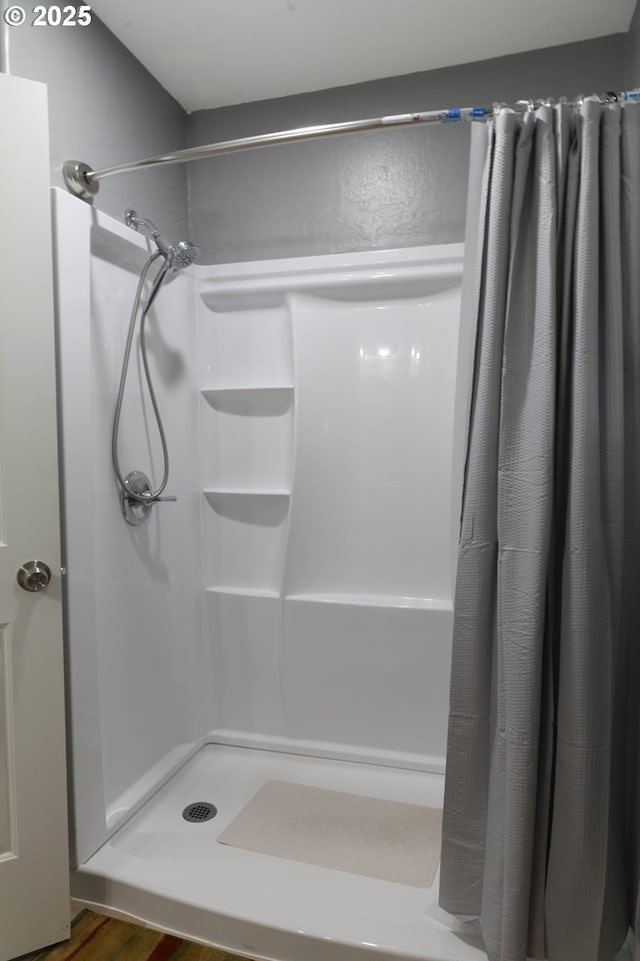 bathroom featuring wood finished floors and a shower stall