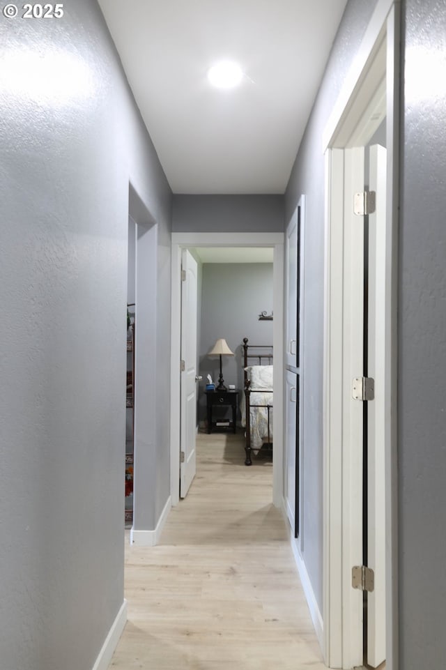 hall with light wood-style floors and baseboards