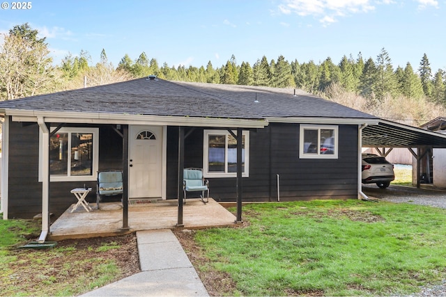 view of front of house with a carport, a shingled roof, and a front yard