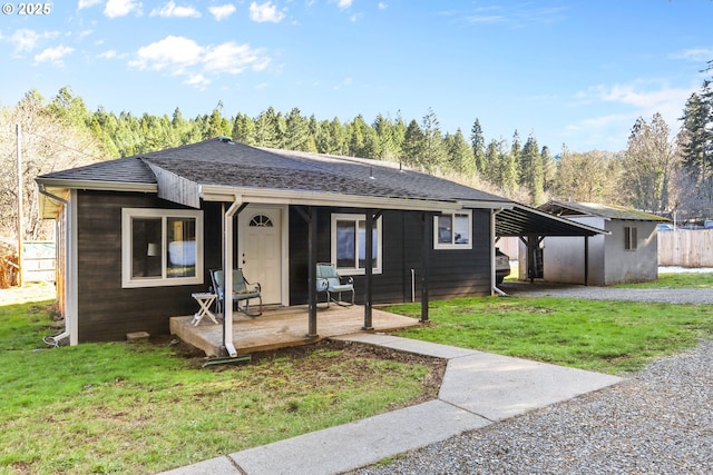 bungalow with a carport, a shingled roof, and a front yard